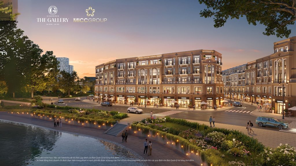Vị trí Vinomes Giảng Võ The Gallery - Thông tin chính thức từ Vinhomes 2 Phối cảnh khu đô thị Vinhomes Giảng Võ – The Gallery vào lúc hoàng hôn, với dãy nhà shophouse cao cấp 5 tầng, các cửa hàng thời trang, quán cà phê, xe cộ di chuyển trên đường và người dân tản bộ bên hồ nước và công viên cây xanh.